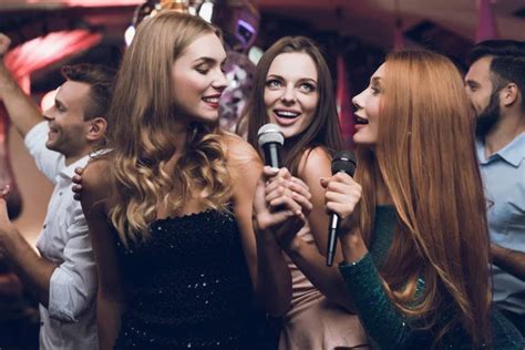 Three Beautiful Girls Sing In A Karaoke Club Behind Them Are Men