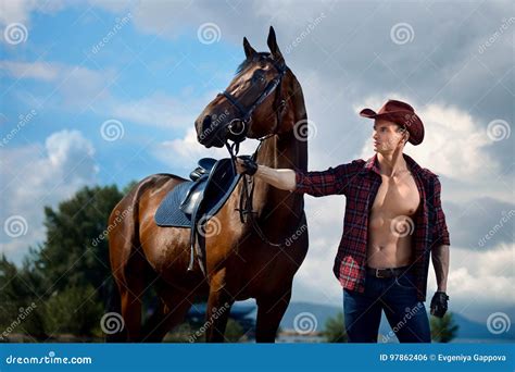 Macho Man Handsome Cowboy And Horse On The Background Of Sky And Water