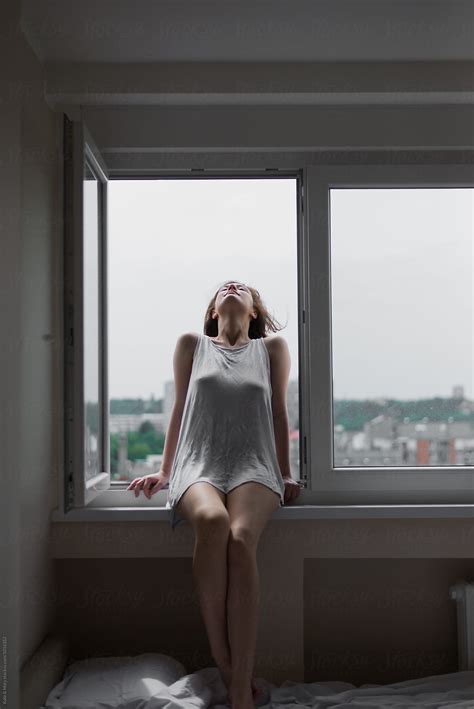 Portrait Of Beautiful Woman Sitting On Window by Katarina Simovic