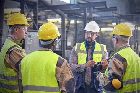 Supervisor talking with steelworkers in steel mill - Stock Photo - Dissolve