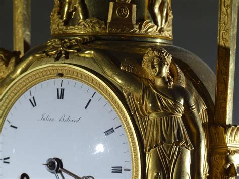 A Gold Clock With Statues On The Sides And Roman Numerals Around Its Face