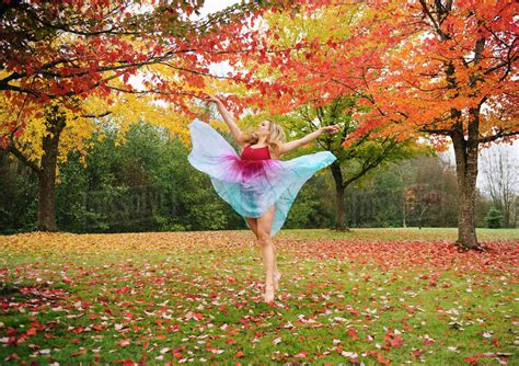 Caucasian Ballerina Dancing In Autumn Leaves In Park Stock Photo