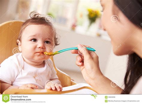 Happy Baby Being Fed in High Chair at Meal Time Stock Photo - Image of