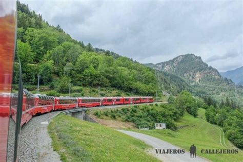 A Red Train Traveling Through A Lush Green Hillside