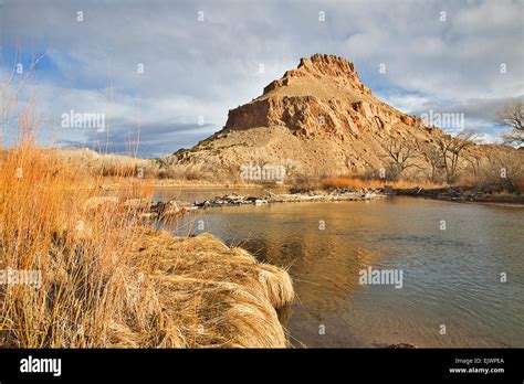 The Chama River Flows Beneath Rugged Cliffs Of Colored Earth Near The