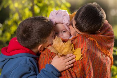 Two Brothers Older And Younger In The Autumn Park Hold Their Sister