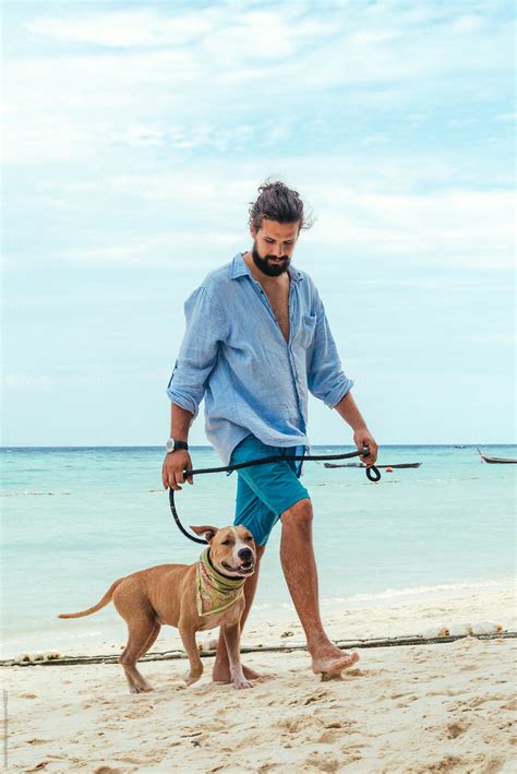 Young Man Walking A Dog On The Beach By Stocksy Contributor Jovana