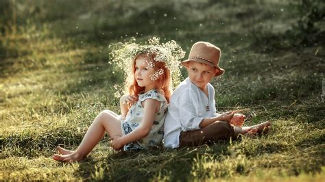 Dziewczynka W Wianku I Chłopczyk W Kapeluszu Siedzą Na Trawie