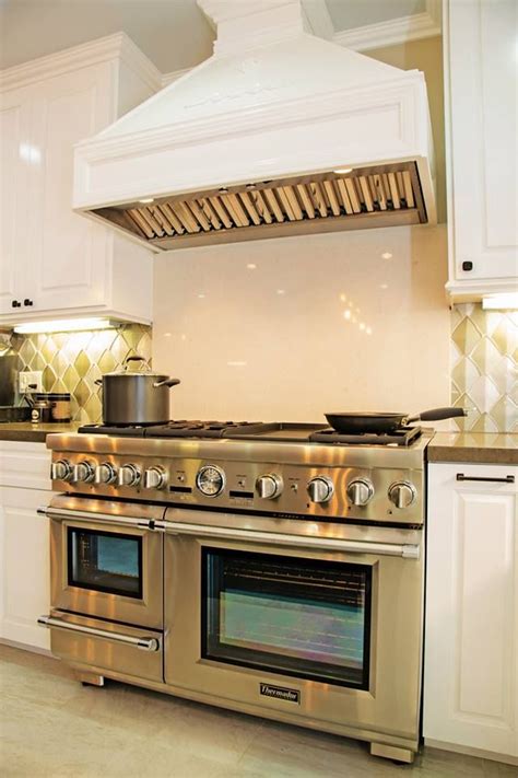 A Stove Top Oven Sitting Inside Of A Kitchen Next To White Cabinets And