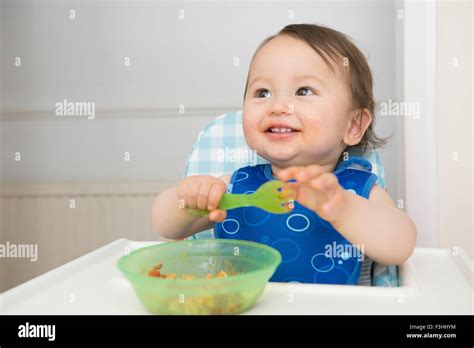 Baby Boy Eating Baby Food In Kitchen High Chair Stock Photo Alamy