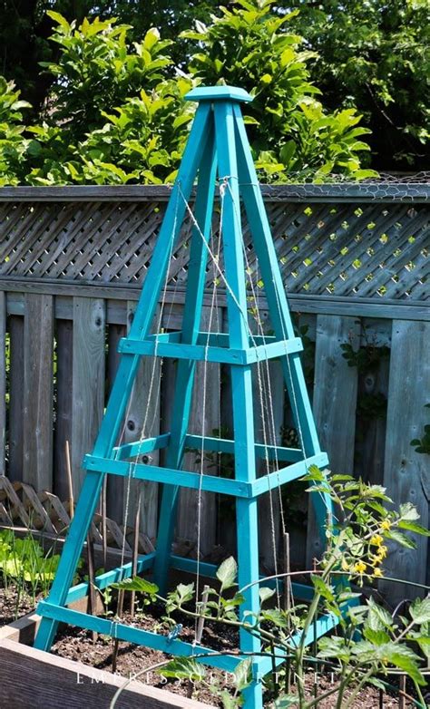 A Tall Blue Wooden Tower Sitting In The Middle Of A Garden Next To A Fence