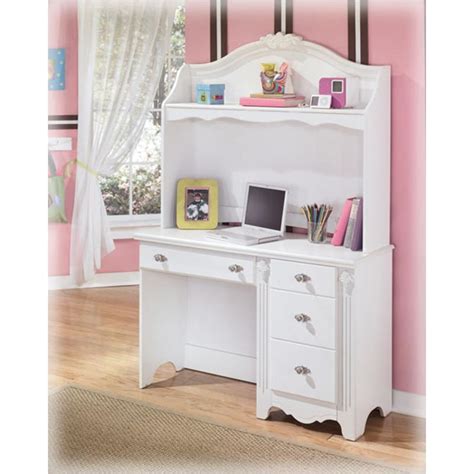 A lilac desk chair sits on a cream rug at a white spindle desk topped with a clear glass lamp and placed beneath a window framed by light purple. B188-23 Ashley Furniture Exquisite - White Bedroom Desk Hutch