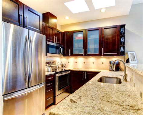 Below are ways top interior designers are using different shades of deep hues from medium brown to black to create an alluring kitchen space. Accentuate Small Kitchens with Dark Cabinets Los Angeles