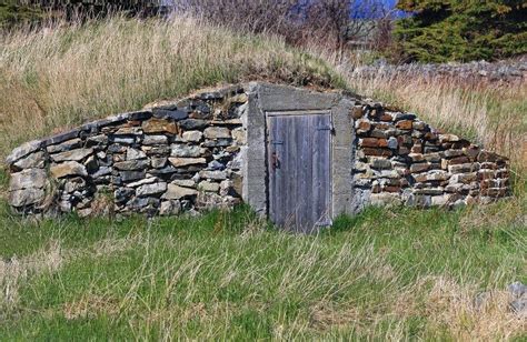 An Old Stone Building With A Door In The Grass