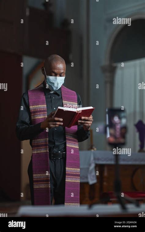 African Priest Standing Near The Altar And Reading The Bible During