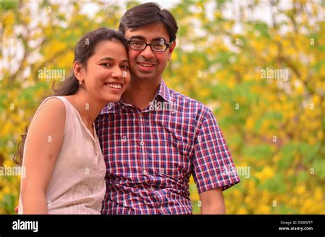 Young Indian Couple Smiling Standing Against Yellow Amaltas Leaves