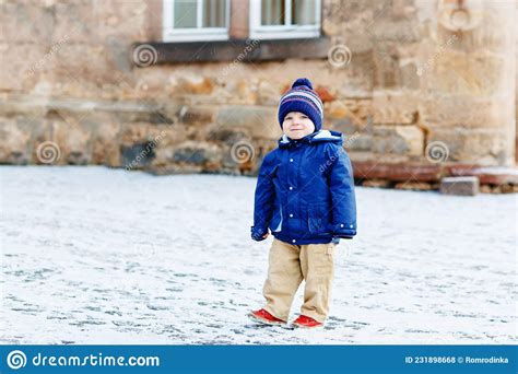 Little Toddler Boy Walking Through The Snowy City During Snowfall Cute