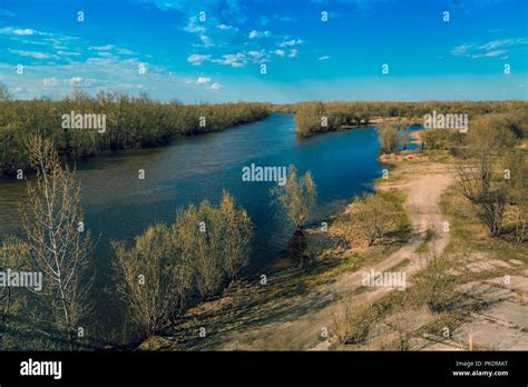 The Siberian River Against A Blue Sky With Clouds Splits Into Two