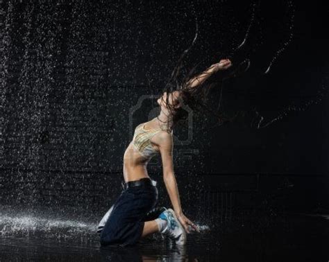 het mooie meisje dansen in water onder de regen op een zwarte achtergrond moderne dansen stock