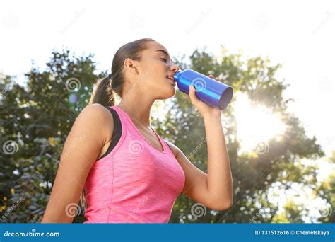 Young Sporty Woman Drinking From Water Bottle In Park Stock Photo