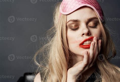 Blonde Woman Smeared Makeup On Her Face On A Gray Background And A Pink Sleep Mask On Her Head