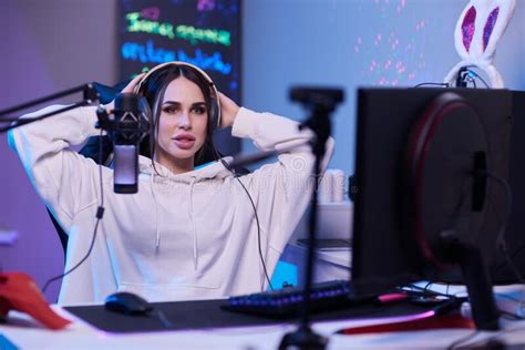 happy woman putting on headphones and playing computer game female gamer in glasses sitting and