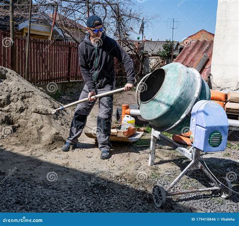 Worker With Shovel Is Digging A Pit On Construction Site Concept Of Hard Work During