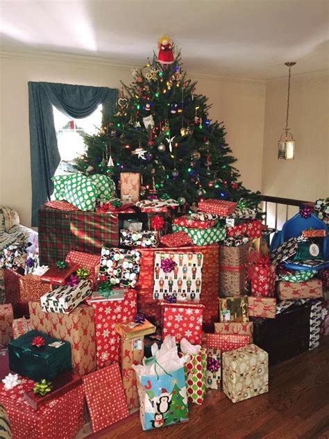 A Christmas Tree With Presents Under It In Front Of A Pile Of Wrapped