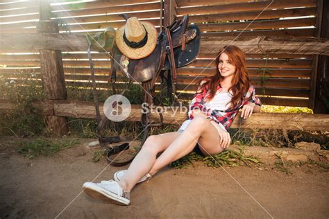 Happy Smiling Young Redhead Cowgirl Resting At The Ranch Fence Royalty