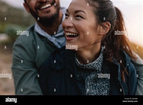 Smiling Asian Woman Being Embraced By Her Boyfriend From Behind Couple