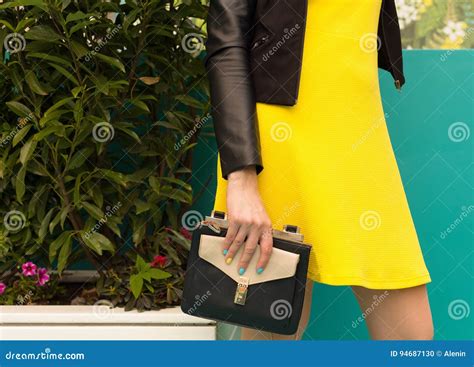 Portrait Girl With In A Short Yellow Dress With A Black Handbag Makes
