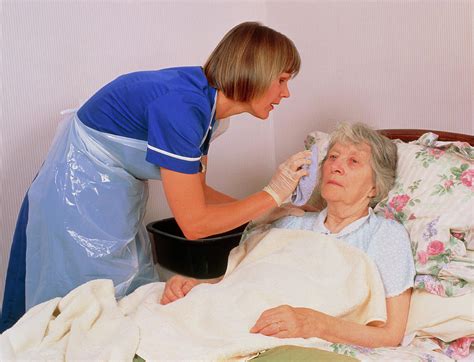 Geriatric Nurse Washing Bedridden Senior Woman Hoodoo Wallpaper