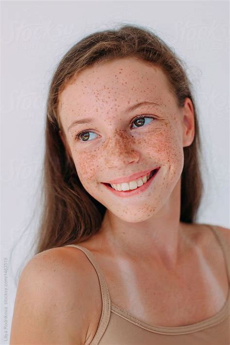 A Woman With Freckles On Her Face Smiling At The Camera While Wearing A Tank Top