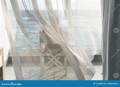 Naked Beautiful Female In The Bikini Sitting On A Chair Behind The Transparent Waving Curtains
