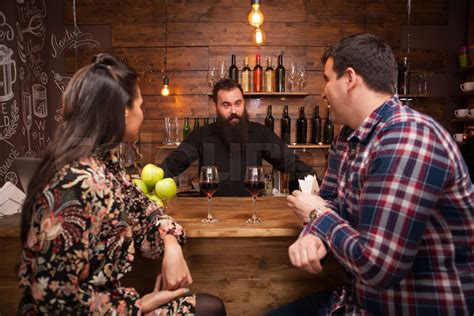 Handsome Bartender Talking With Customers At Bar Counter In A Pub Stock Image Colourbox