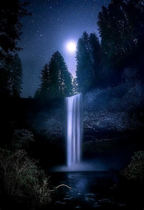 A Waterfall In The Middle Of A Forest At Night