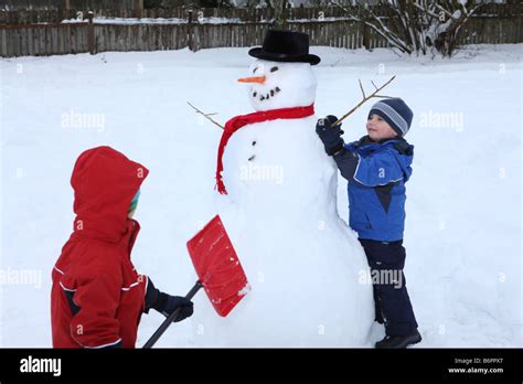 Two Young Boys Building Snowman Stock Photo Alamy