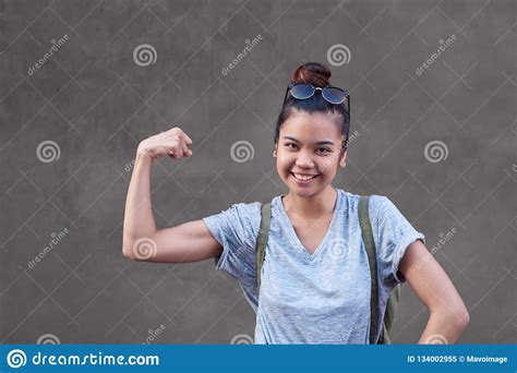 Joyful Asian Woman Smiling While Flexing Her Bicep Outside Stock Image
