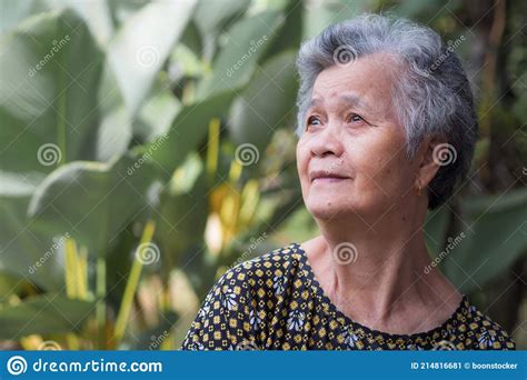 A Portrait Of An Elderly Woman Smiling And Looking Up While Standing In