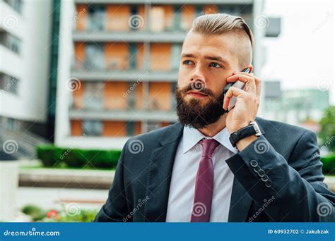Young Bearded Businessman Using Mobile Phone Outside The Office Stock