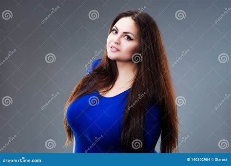 brunette plus size fashion model in blue dress fat woman with long hair on gray background
