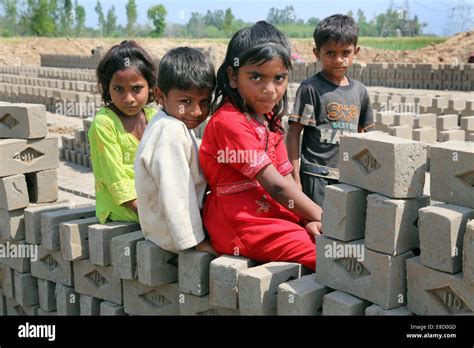 Children Of Brickyard Worker On A Wall Of Clay Bricks On A Field Of The