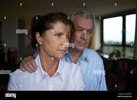 Elderly couple together art home, the husband is seen comforting his