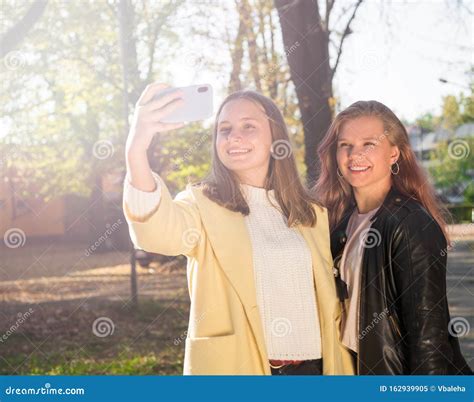 Two Beautiful Teen Girls Taking Selfie On The Phone In Sunny Autumn Park Stock Image Image Of