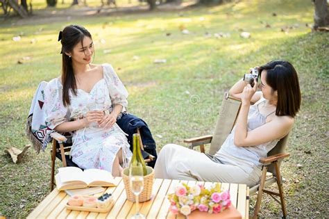 Charming Asian Woman Picnic In The Park With Her Friend Taking Photo