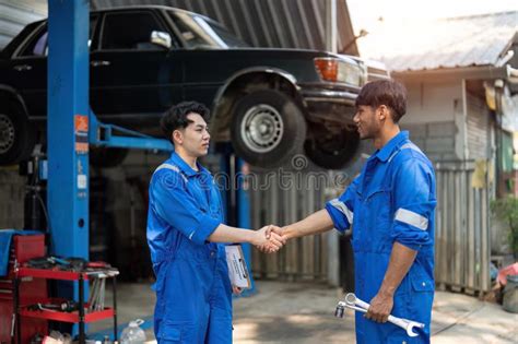 Two Asian Automotive Mechanic Repairman Handshake In Garage Vehicle