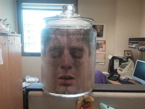 A Mans Face In A Jar On Top Of A Refrigerator