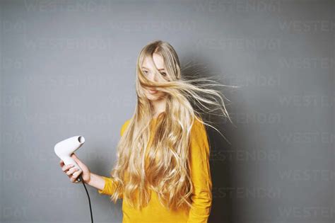 Portrait Of Young Woman Blowing Hair Against Gray Background Stock Photo