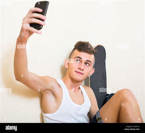 Teenage Guy Smiling And Doing Selfie On Smartphone At Home Stock Photo