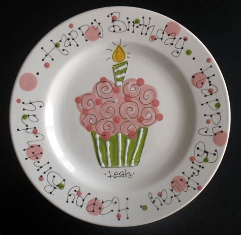 A White Plate With Pink Flowers And A Birthday Candle On The Side That